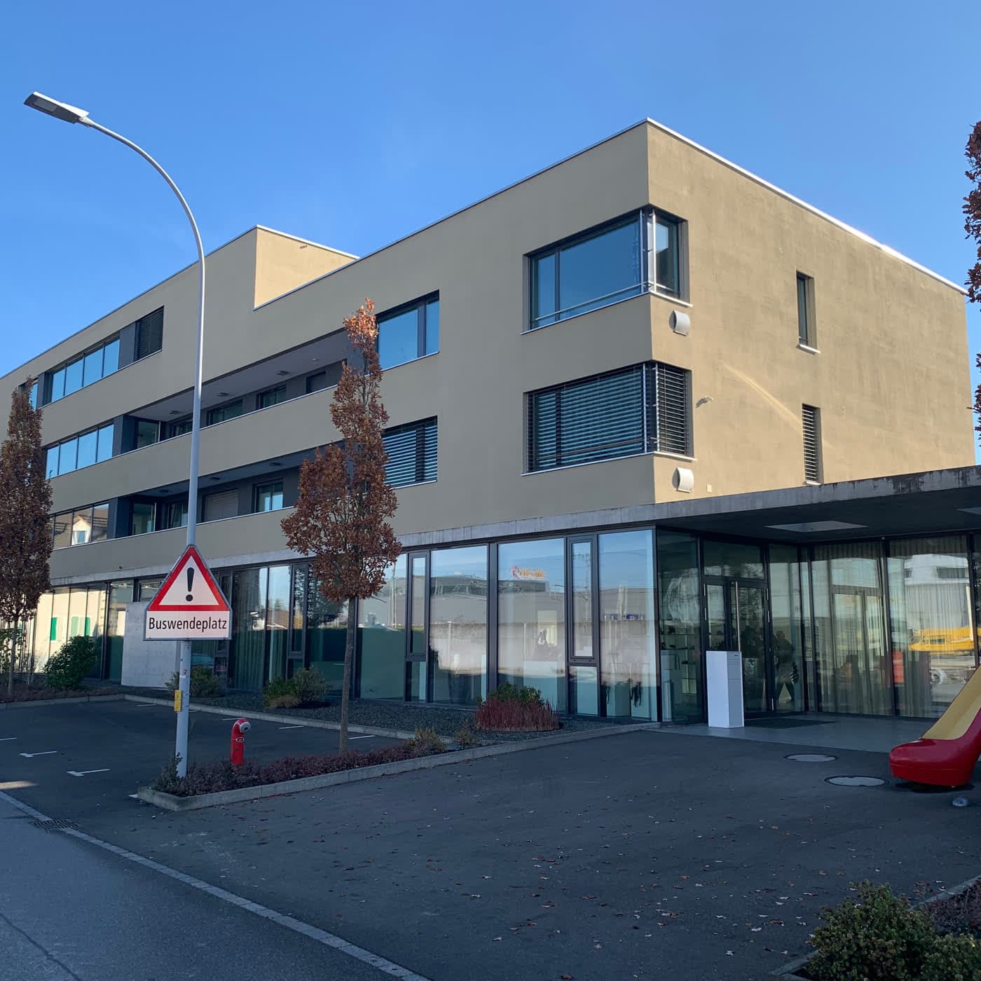 Dreigeschossiges Geschäftshaus mit verglastem Erdgeschoss und Vorplatz