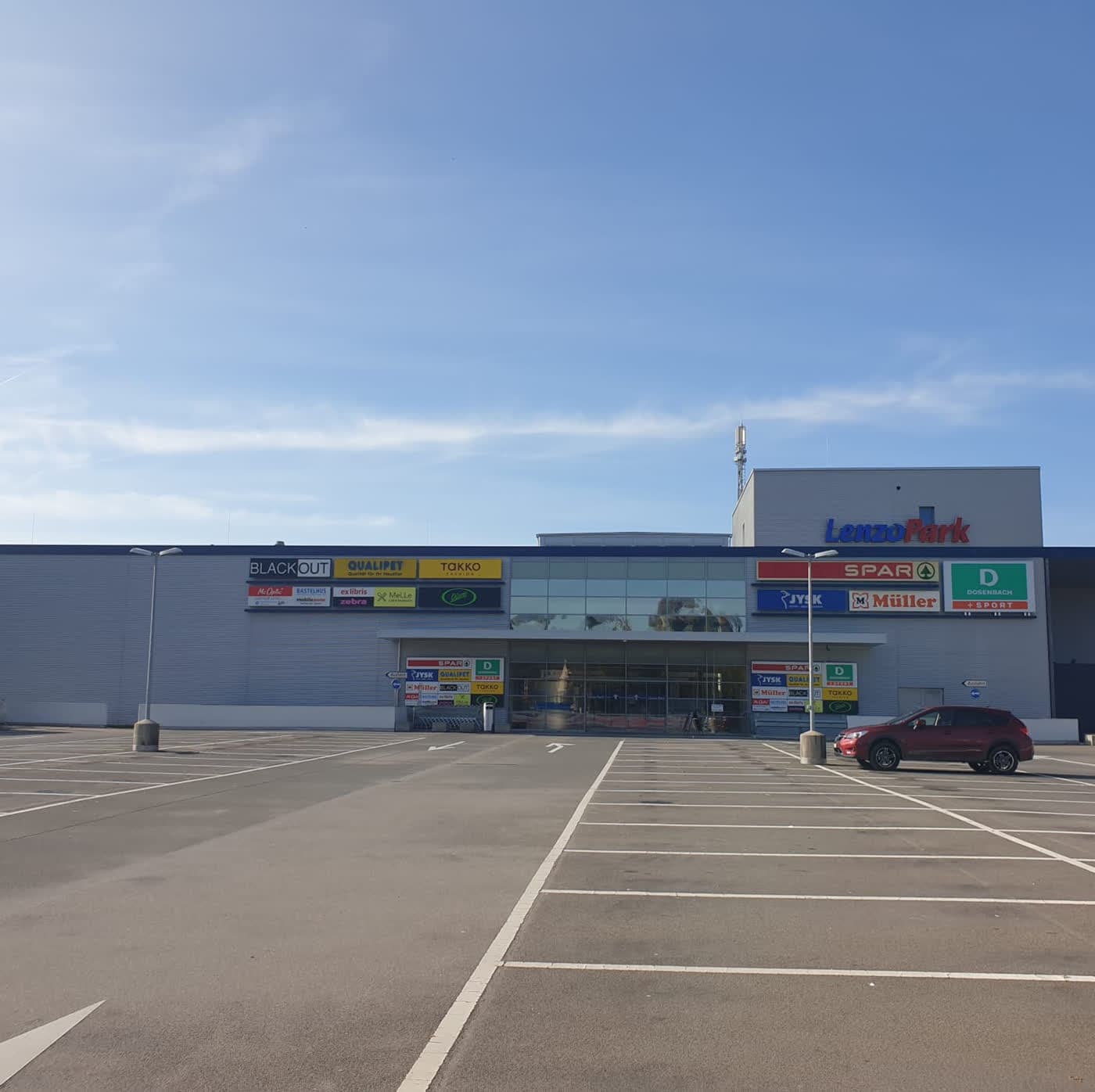 Einkaufszentrum mit langer Ladenfront und leerem Parkfeld davor