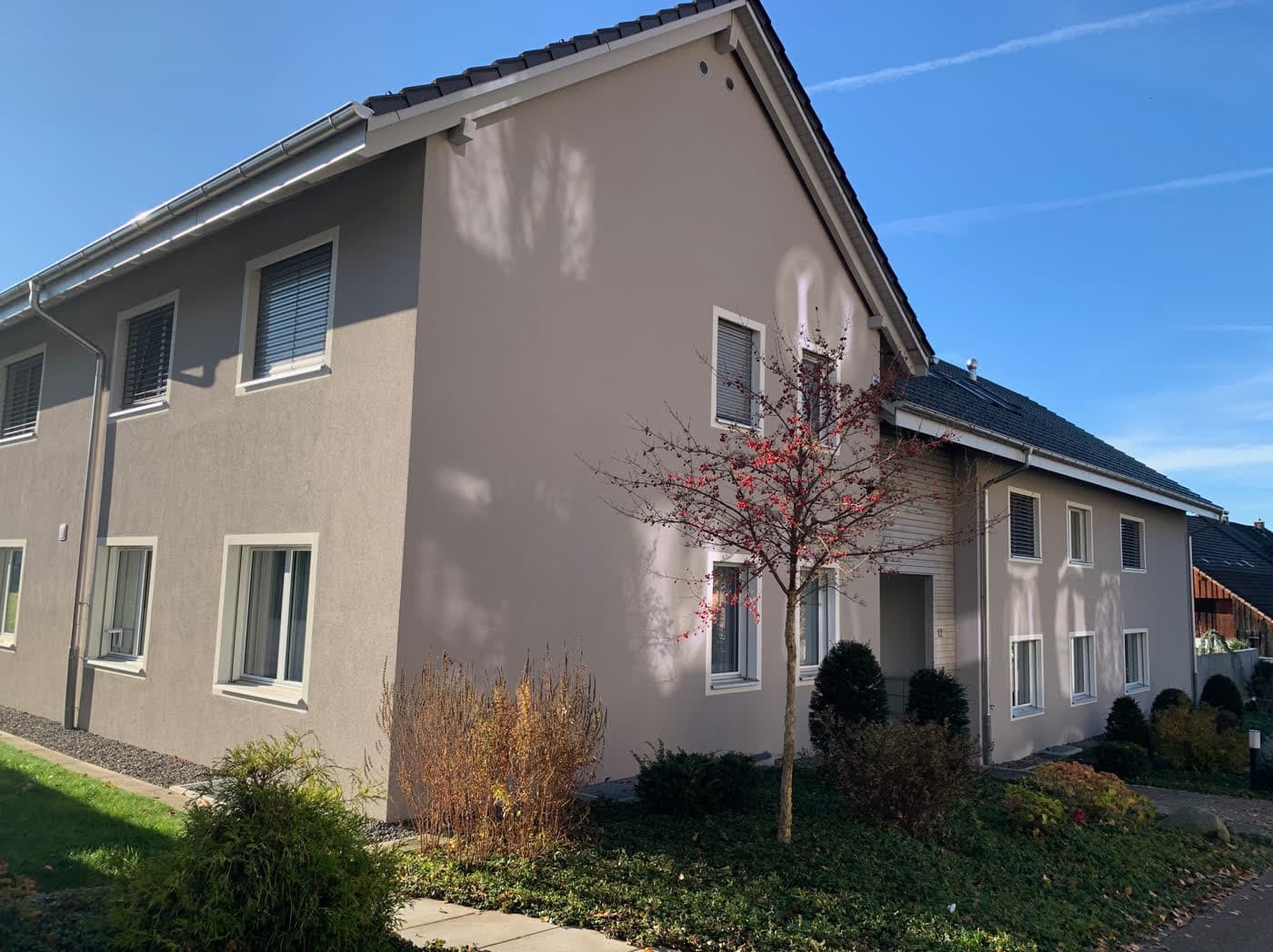 Verputztes Mehrfamilienhaus mit Satteldach und bepflanztem Vorgarten