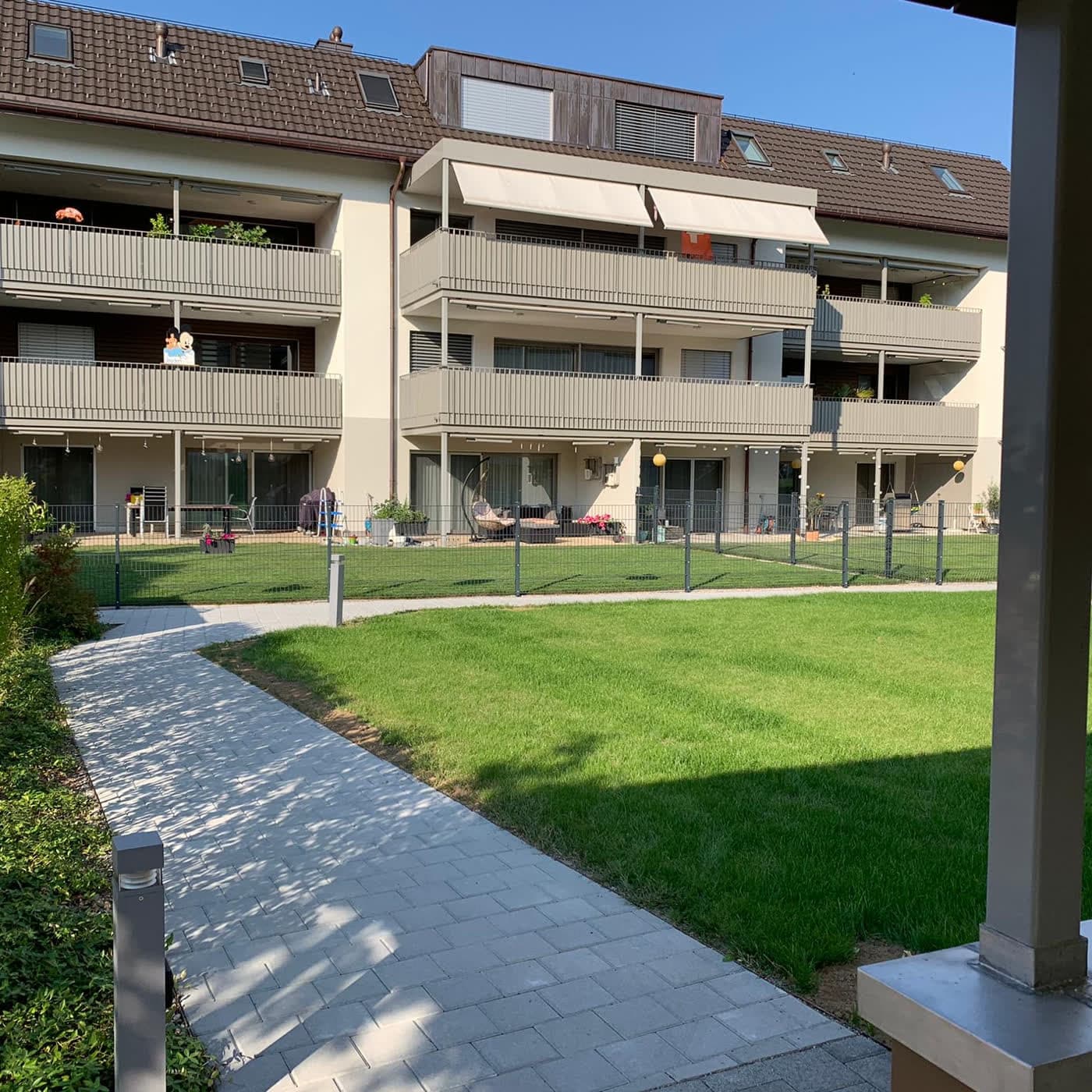 Innenhof der Wohnüberbauung mit Rasenfläche und gepflastertem Gehweg
