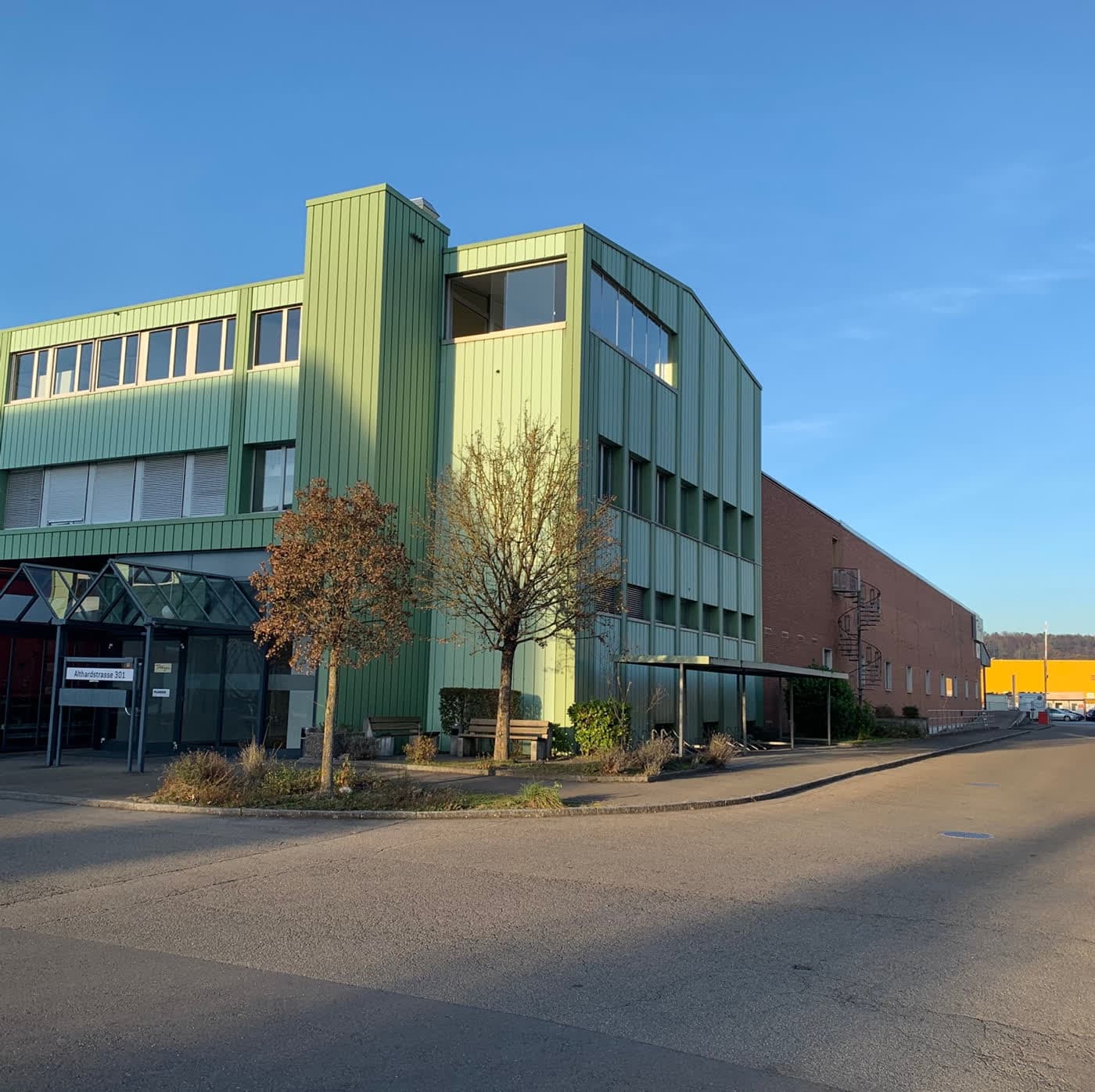 Gewerbebau mit grüner Metallfassade an einer Quartierstrasse
