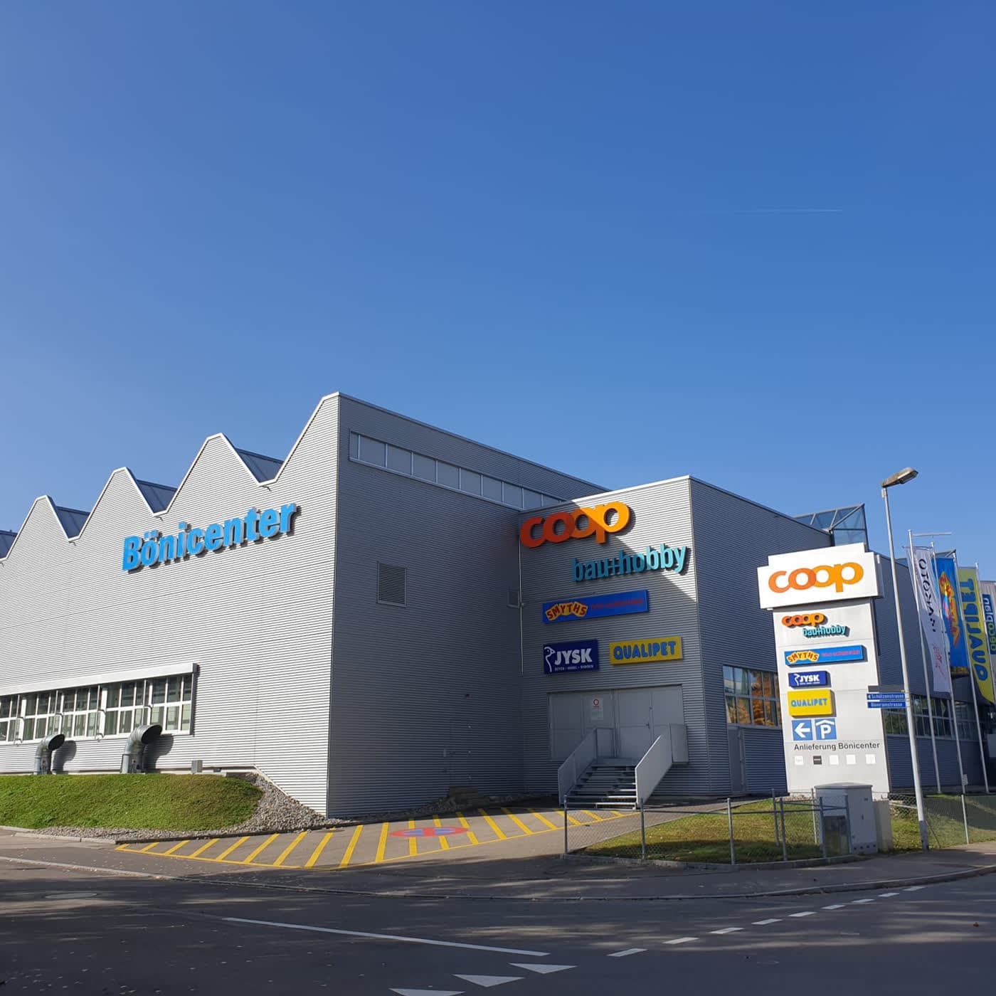 Fachmarktzentrum mit heller Wellblechfassade und einem Werbepylon an der Zufahrt