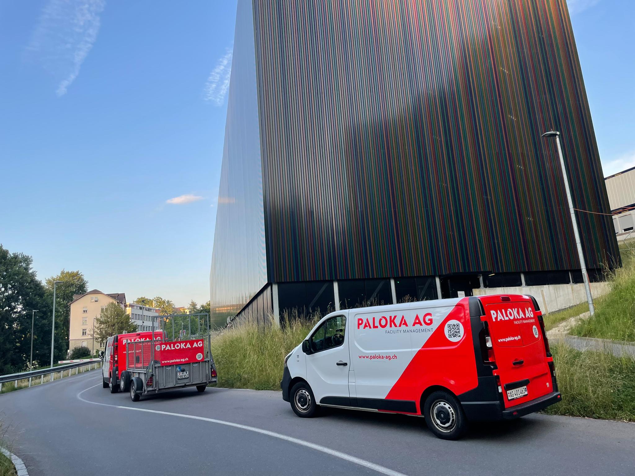 Zwei Servicefahrzeuge der Paloka AG mit Anhänger vor einem modernen Gebäude in der Deutschschweiz